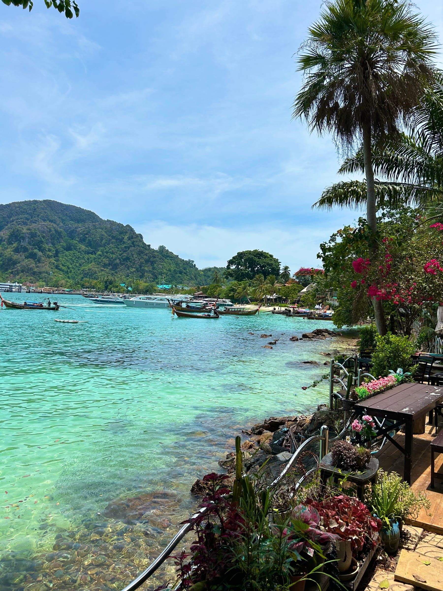 Turquoise bay with longtail boats and green hills